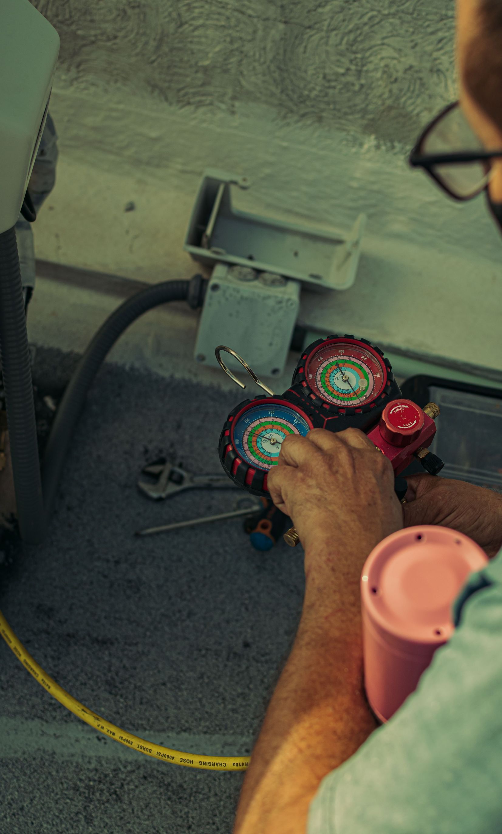 Professional technician adjusting a refrigerant manifold gauge for air conditioning maintenance.